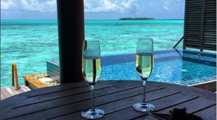 02 glasses of champagne on a table over seeing a infinity pool over a turquoise lagoon in Maldives