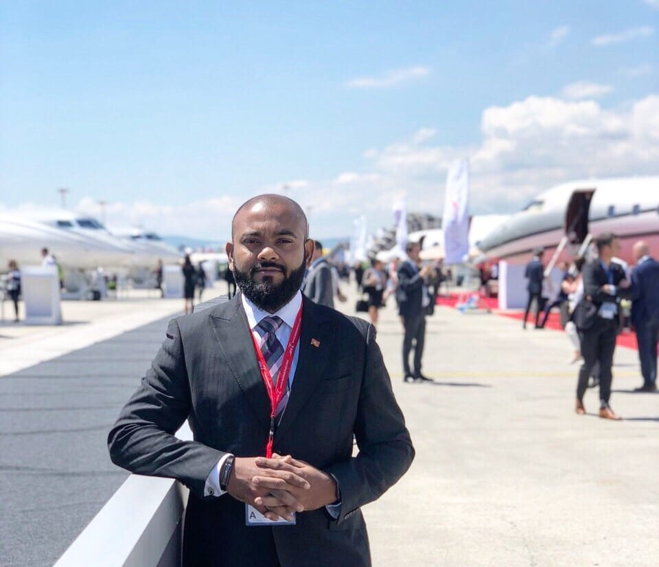 Ahmed Arshad, Director of Ground Operations at avia maldives standing on the tarmac in airport with a private jet in the background.