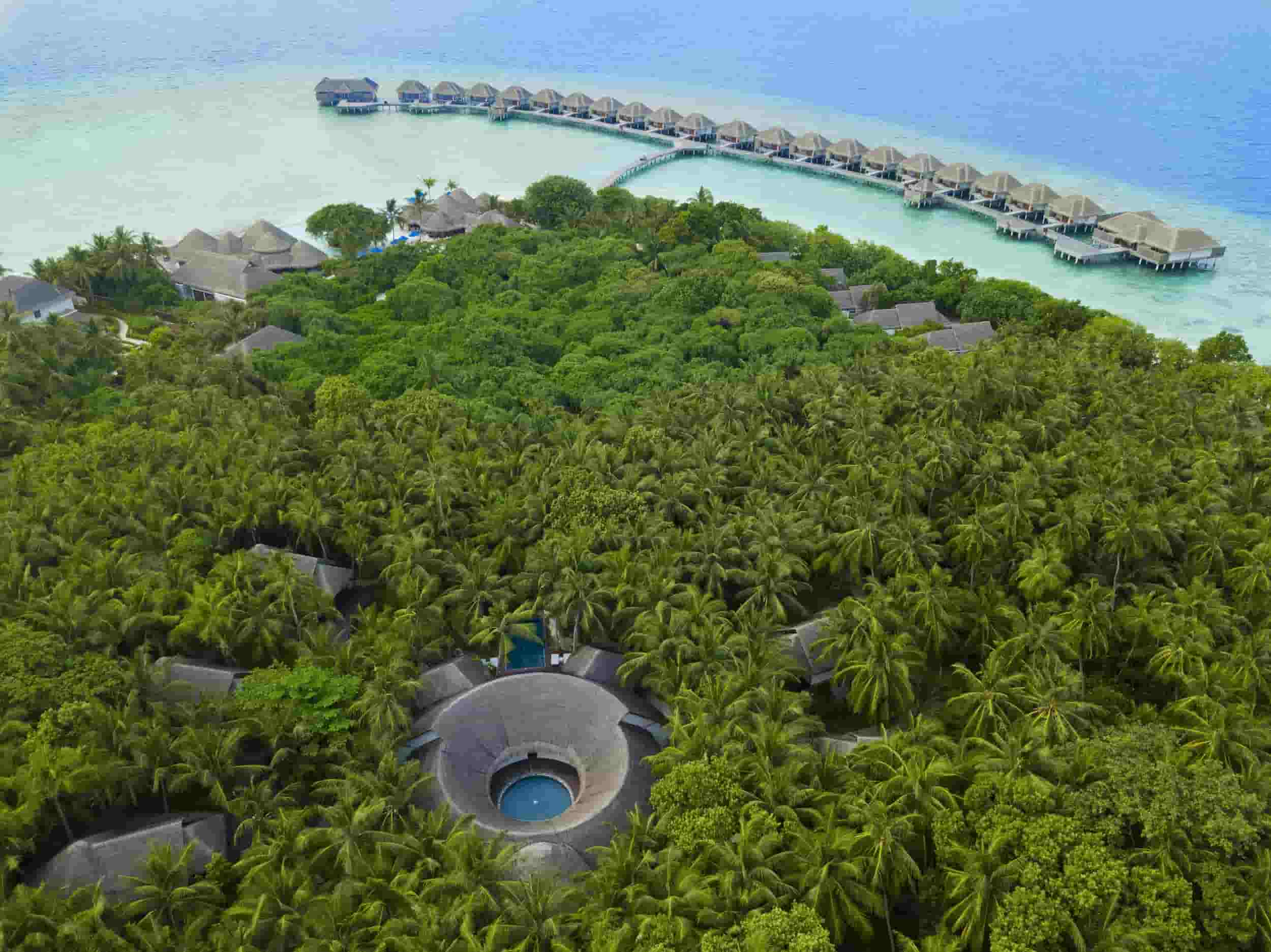 drone image of Dusit International property in maldives. With lush green and over water villas above the turquoise waters