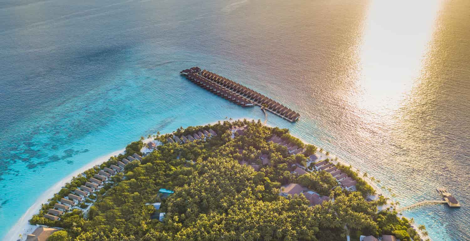 Drone image of Reethi Faru Resort. lish green trees , white sandy beaches and crystal clear waters