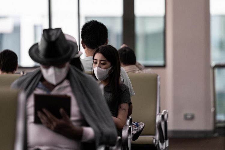 women with mask at airport traveling with restrictions
