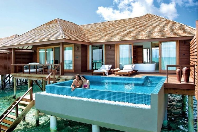 tourists enjoying holiday in maldives on pool with sun beds near